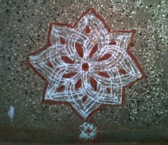 Traditional Kolam made with lines and filled with red stone color